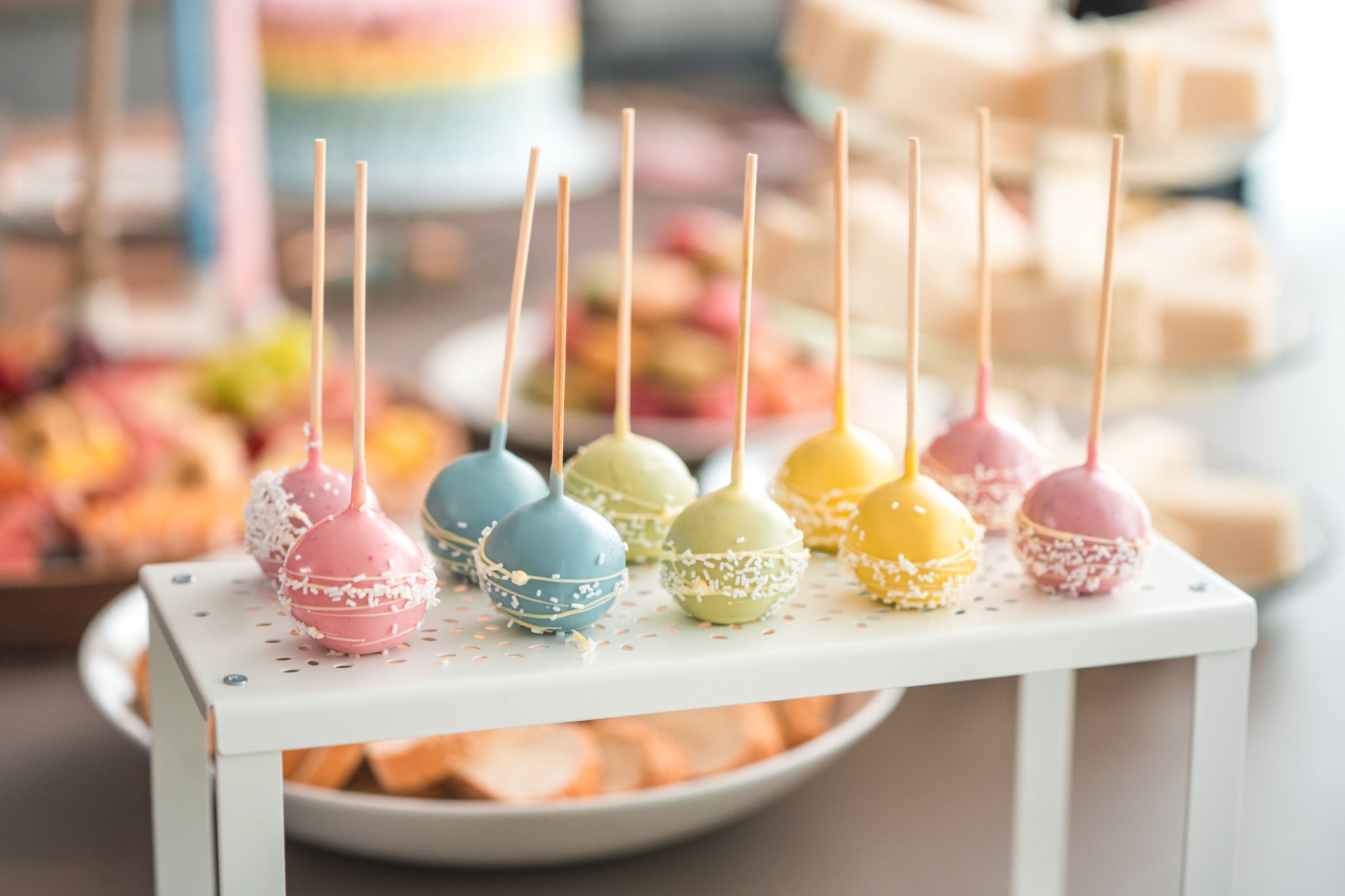 Colorful pastel cake pops on a white display stand catered by Asher Cuisine for a DFW celebration event